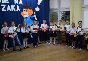 Grupa dzieci trzyma w ręku gitary, grają na nich z rozmachem i radością